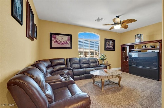 carpeted living area with ceiling fan and baseboards