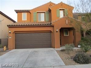 mediterranean / spanish house featuring an attached garage, concrete driveway, and stucco siding