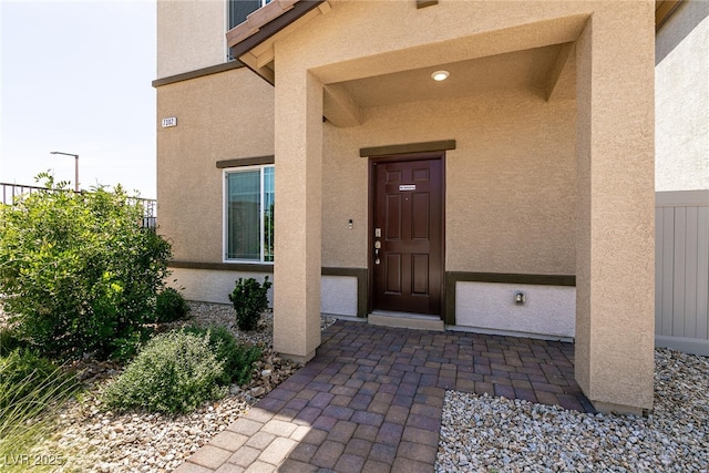 entrance to property with stucco siding and fence