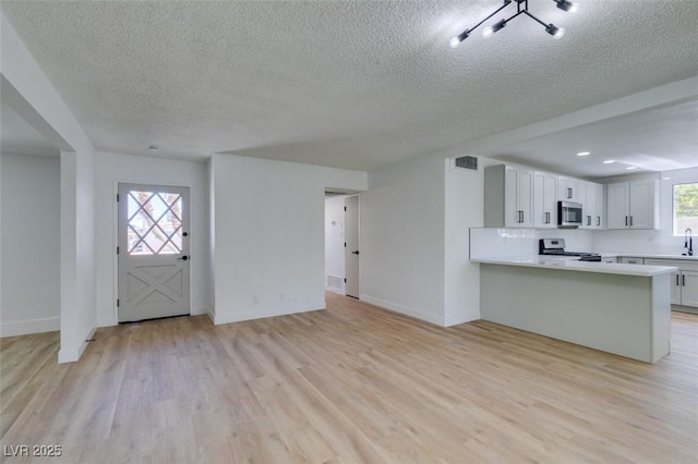212 View Dr, Las Vegas, NV 89107 - unfurnished living room featuring a textured ceiling, light wood finished floors, baseboards, and a sink