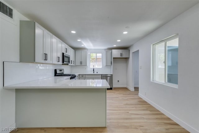 212 View Dr, Las Vegas, NV 89107 - kitchen with stainless steel appliances, recessed lighting, a peninsula, light countertops, and light wood finished floors