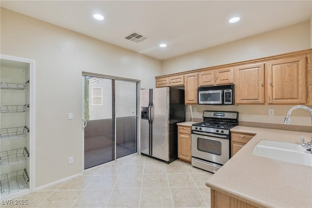 kitchen with stainless steel appliances, a sink, light countertops, recessed lighting, and light tile patterned floors