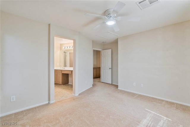 unfurnished bedroom with light colored carpet, baseboards, connected bathroom, and a ceiling fan