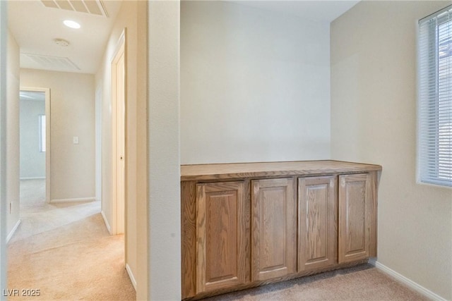 hallway with light carpet, baseboards, and plenty of natural light