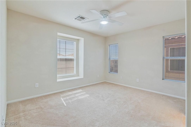 carpeted spare room with a ceiling fan and baseboards