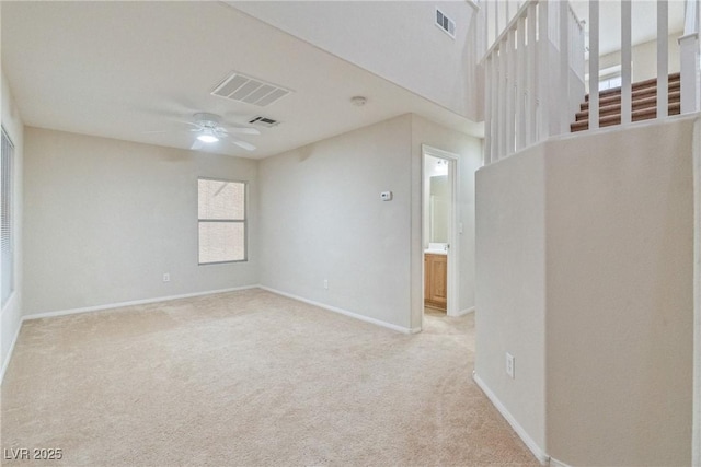 empty room featuring ceiling fan, light colored carpet, and baseboards