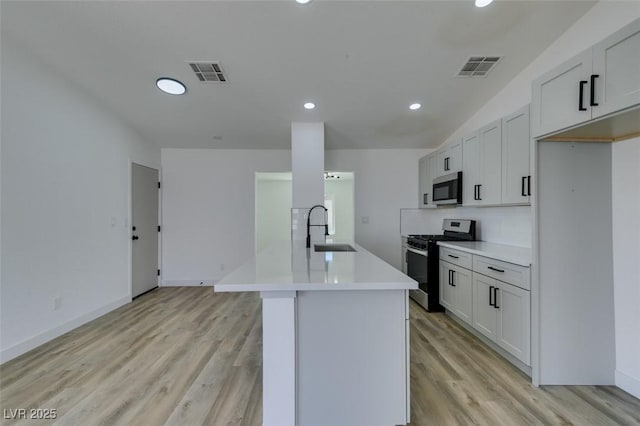 kitchen with gas range, stainless steel microwave, a sink, light wood-style flooring, and recessed lighting