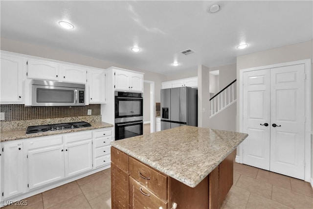 2257 Norway Pine Ct, Las Vegas, NV 89134 - kitchen featuring stainless steel appliances, white cabinetry, a center island, light tile patterned floors, and tasteful backsplash