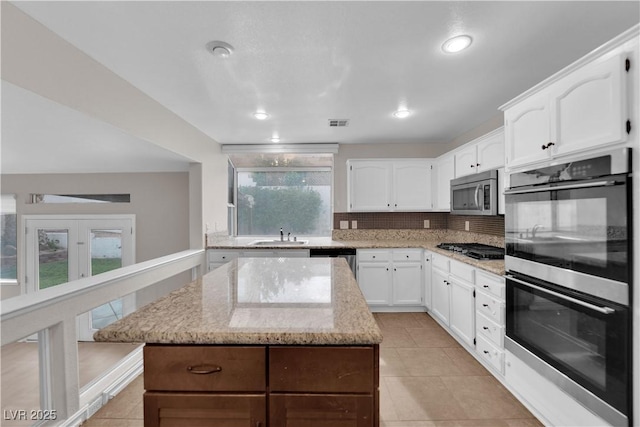 2257 Norway Pine Ct, Las Vegas, NV 89134 - kitchen with stainless steel appliances, tasteful backsplash, a center island, light tile patterned floors, and recessed lighting