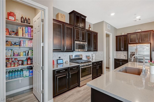 468 Harvest Rain, Las Vegas, NV 89011 - kitchen featuring stainless steel appliances, a sink, light wood-style floors, decorative backsplash, and light countertops