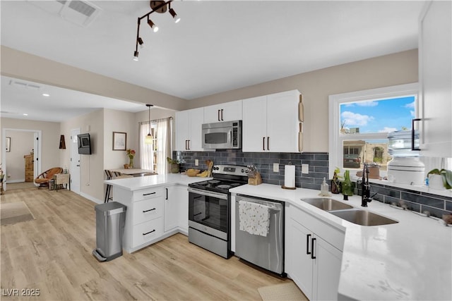 1320 Wengert Ave, Las Vegas, NV 89104 - kitchen featuring stainless steel appliances, a sink, a peninsula, decorative backsplash, and light countertops