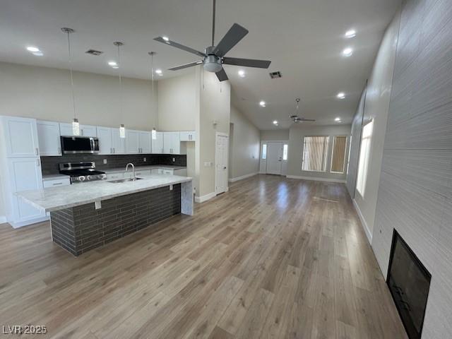 8847 W Katie Ave, Las Vegas, NV 89147 - kitchen with stainless steel appliances, a sink, ceiling fan, high vaulted ceiling, and white cabinets