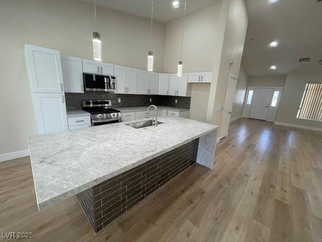 8847 W Katie Ave, Las Vegas, NV 89147 - kitchen with stainless steel appliances, a sink, baseboards, white cabinets, and tasteful backsplash