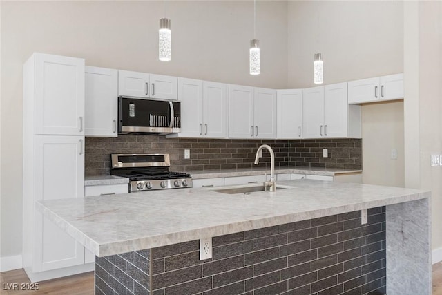 8847 W Katie Ave, Las Vegas, NV 89147 - kitchen featuring appliances with stainless steel finishes, a sink, a towering ceiling, white cabinetry, and light countertops