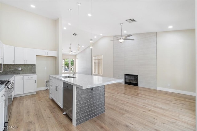 8847 W Katie Ave, Las Vegas, NV 89147 - kitchen featuring a sink, stainless steel appliances, ceiling fan, a large fireplace, and white cabinets