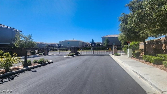 9198 Harbin Ave, Las Vegas, NV 89148 - view of asphalt road featuring sidewalks, a gated entry, a gate, and curbs