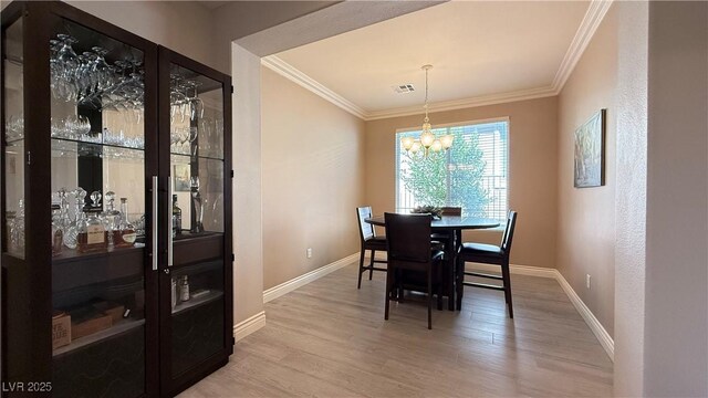 4299 Fiore Bella Blvd, Las Vegas, NV 89135 - dining space featuring light wood finished floors, crown molding, a chandelier, baseboards, and a dry bar