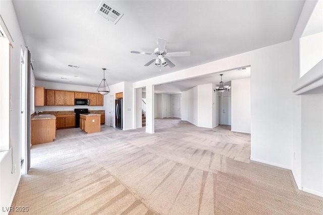 unfurnished living room featuring light carpet, a chandelier, a ceiling fan, and baseboards