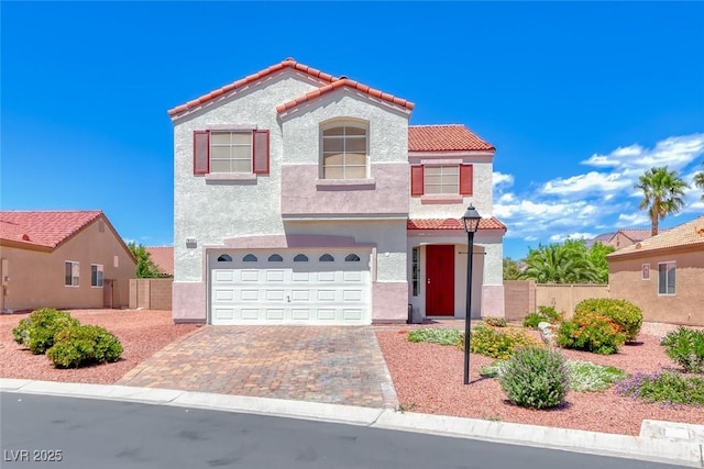 mediterranean / spanish-style house featuring a tile roof, a garage, fence, stucco siding, and decorative driveway