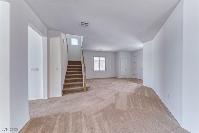 carpeted spare room featuring stairway and baseboards