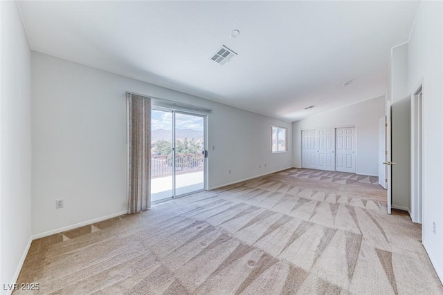 spare room featuring lofted ceiling, light carpet, and baseboards