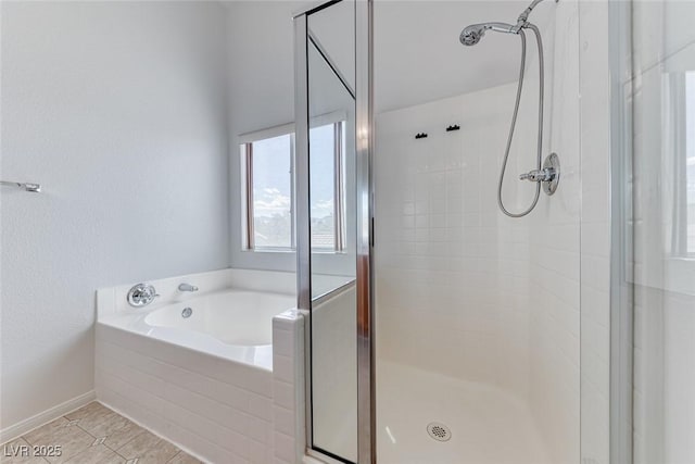 full bathroom with a stall shower, a bath, baseboards, and tile patterned floors