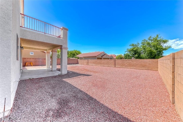 fenced backyard with a balcony and a patio area