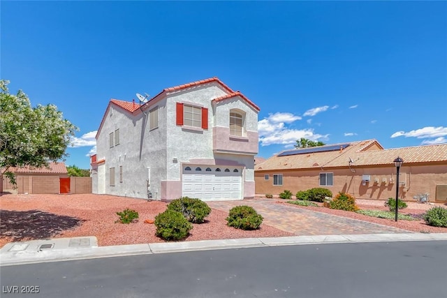 view of front of home featuring an attached garage, a tiled roof, stucco siding, and driveway