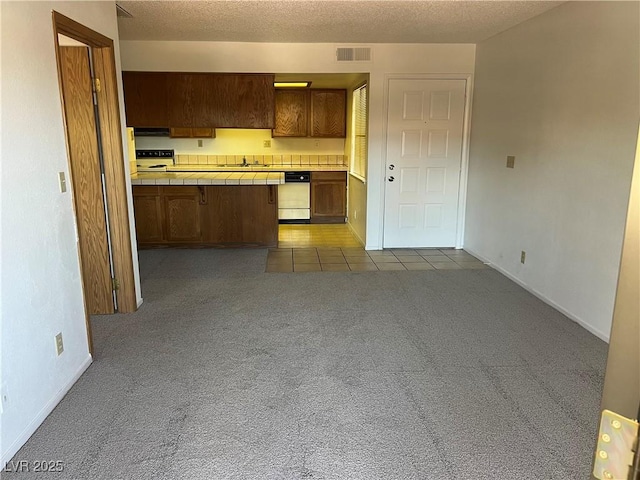 4121 Gannet Cir Unit 414, Las Vegas, NV 89103 - kitchen featuring tile counters, a sink, dark colored carpet, dishwashing machine, and a peninsula
