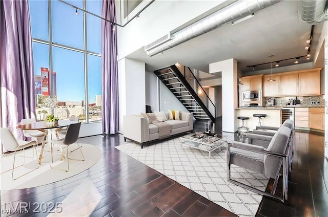 360 E Desert Inn Rd Unit 807, Las Vegas, NV 89109 - living room featuring stairway, track lighting, dark wood-style flooring, wine cooler, and a towering ceiling