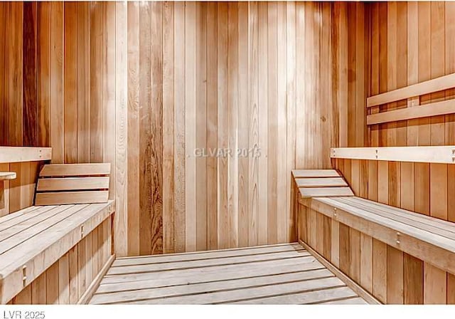 relaxing sauna featuring wooden walls