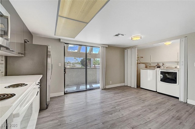 laundry room featuring light wood finished floors, baseboards, and washer and clothes dryer