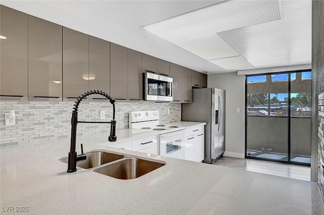 kitchen with appliances with stainless steel finishes, a sink, tasteful backsplash, and light stone countertops