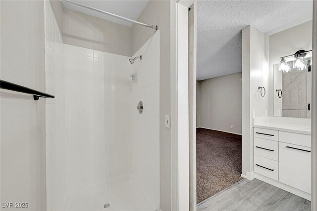 full bath featuring a shower, a textured ceiling, vanity, and wood finished floors