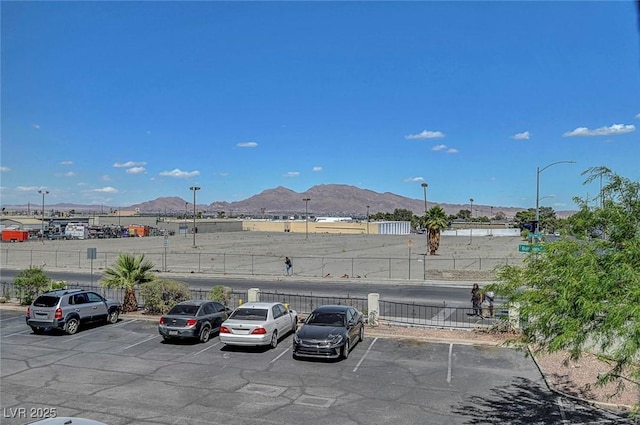 uncovered parking lot featuring fence and a mountain view