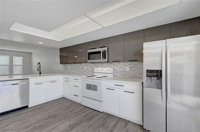 kitchen with stainless steel appliances, modern cabinets, backsplash, a sink, and light wood-style floors