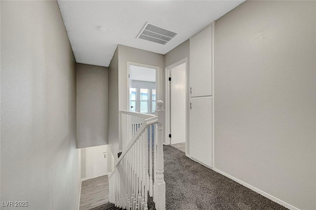 hallway with an upstairs landing, carpet, and baseboards