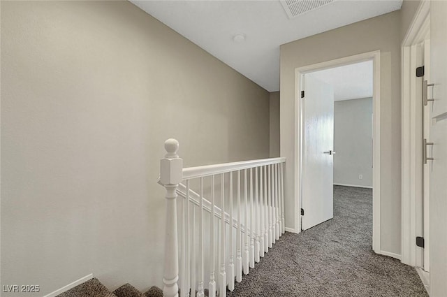 hallway featuring carpet floors, an upstairs landing, and baseboards