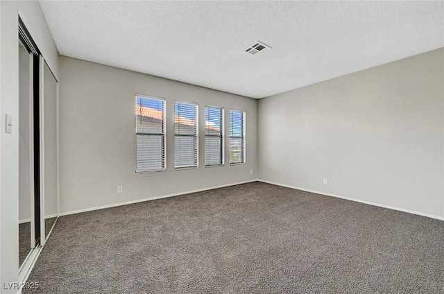 carpeted spare room with a textured ceiling and baseboards