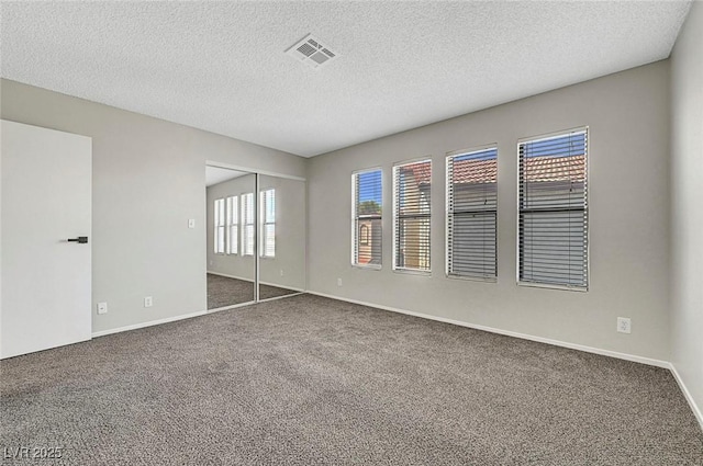unfurnished bedroom featuring carpet flooring, a closet, a textured ceiling, and baseboards