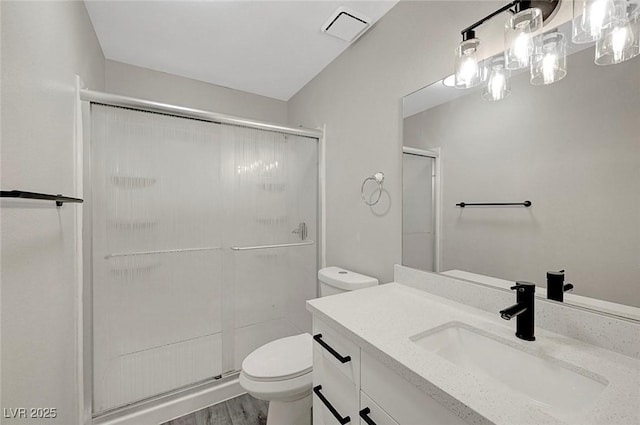 bathroom with toilet, a shower stall, vanity, and wood finished floors