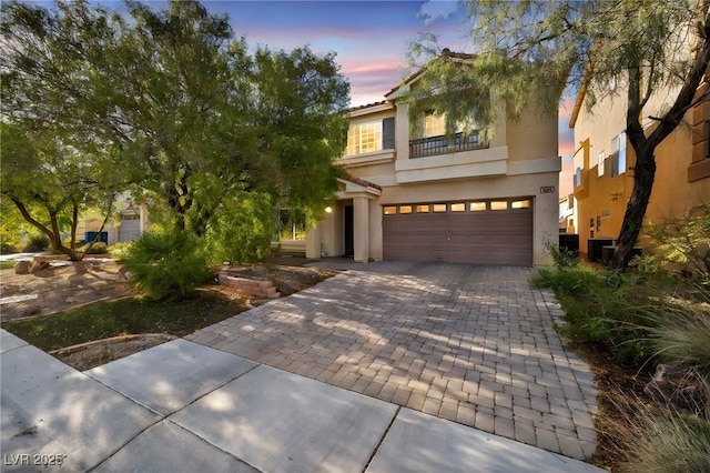 mediterranean / spanish-style home featuring a balcony, stucco siding, a garage, and decorative driveway