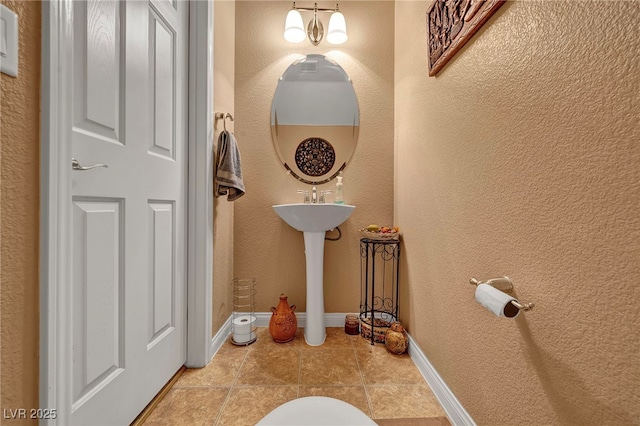 half bath with baseboards and tile patterned floors