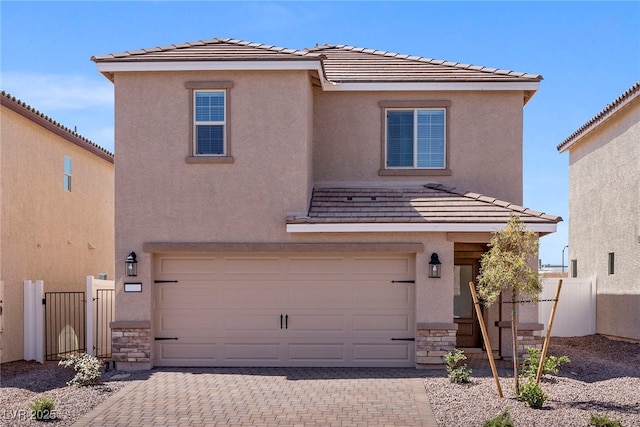 view of front of property featuring stone siding, fence, a garage, and stucco siding