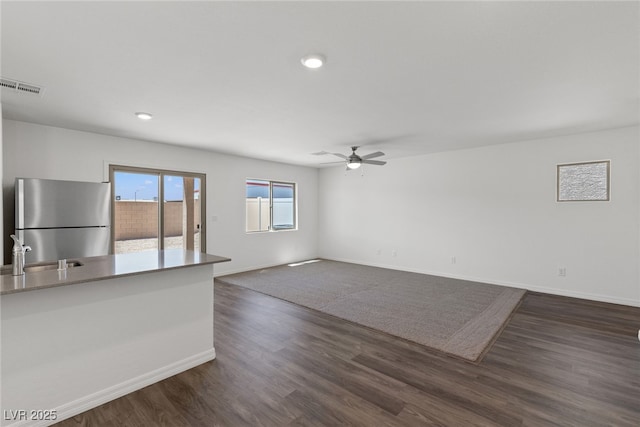 unfurnished living room with a sink, ceiling fan, baseboards, dark wood-style floors, and recessed lighting