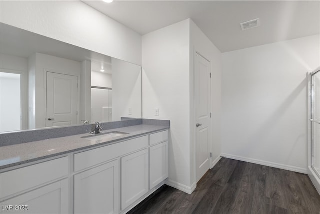 bathroom with wood finished floors, an enclosed shower, baseboards, and vanity