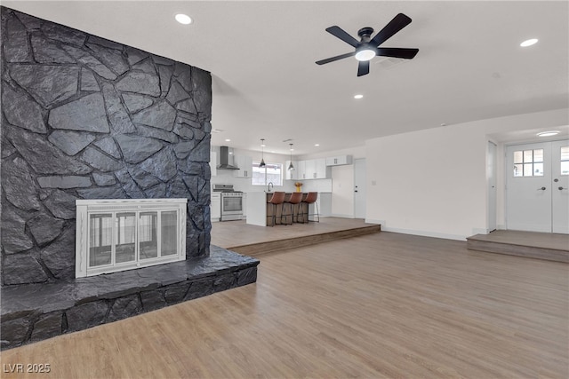 405 Oil Lantern Ln, Las Vegas, NV 89145 - unfurnished living room with ceiling fan, light wood finished floors, recessed lighting, plenty of natural light, and a stone fireplace