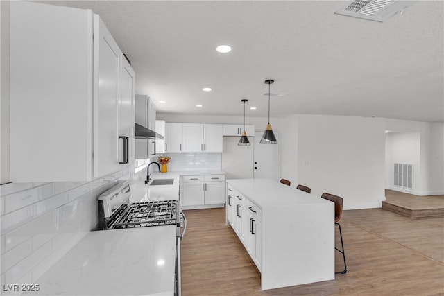 405 Oil Lantern Ln, Las Vegas, NV 89145 - kitchen featuring gas stove, a sink, a kitchen bar, tasteful backsplash, and wall chimney exhaust hood