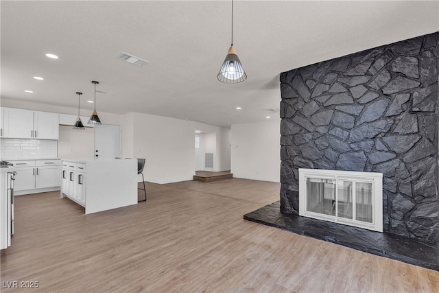 405 Oil Lantern Ln, Las Vegas, NV 89145 - unfurnished living room with light wood-style flooring, recessed lighting, baseboards, and a stone fireplace