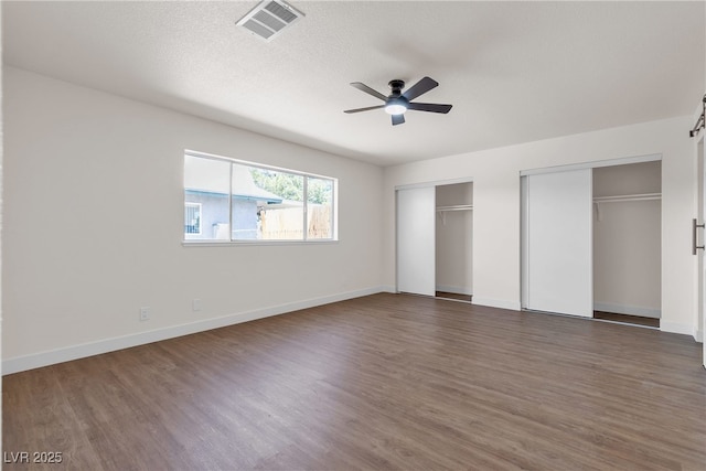 405 Oil Lantern Ln, Las Vegas, NV 89145 - unfurnished bedroom featuring two closets, dark wood-style flooring, baseboards, and a textured ceiling